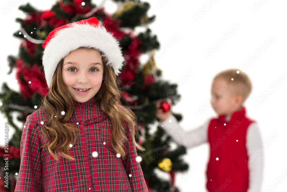 Festive little girl smiling at camera with boy behind against snow Festive little girl smiling at camera with boy behind against snow