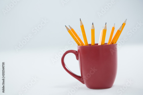 Yellow color pencils kept in mug on white background