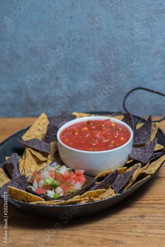 Chips, salsa and pico de gallo in a black platter on wooden board