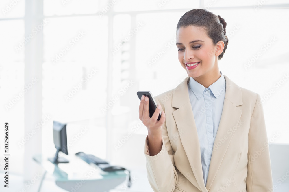 Content smart brown haired businesswoman looking at her mobile phone Content smart brown haired businesswoman looking at her mobile phone