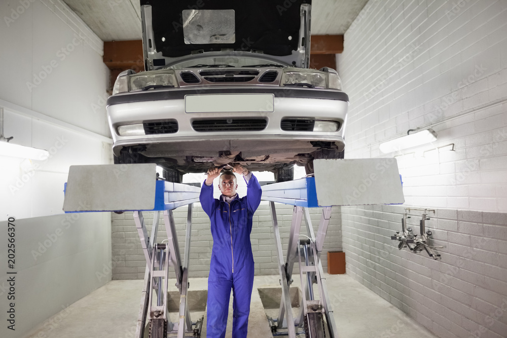 Fototapeta premium Mechanic standing while repairing a car with tools