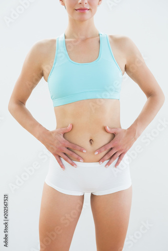 Mid section of a fit woman in sportswear with hands on belly