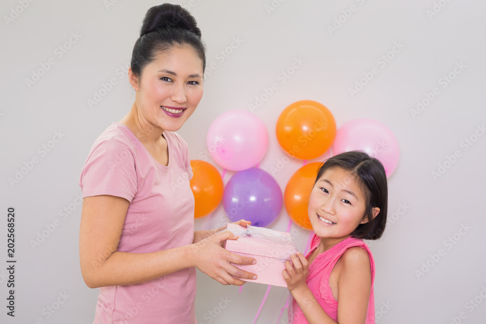 Woman giving gift box to a little girl at a birthday party Woman giving gift box to a little girl at a birthday party