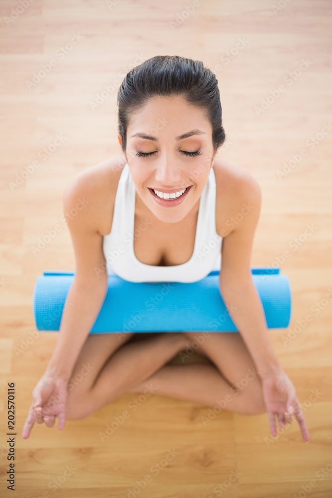 Calm woman with her exercise mat sitting in lotus pose Calm woman with her exercise mat sitting in lotus pose
