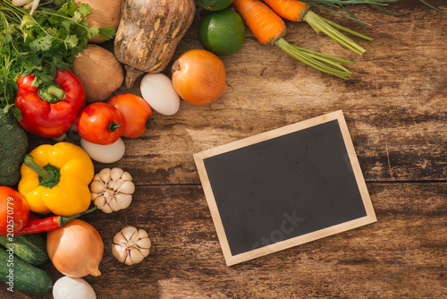 Cooking classes concept. Fresh vegetables around chalkboard on table.