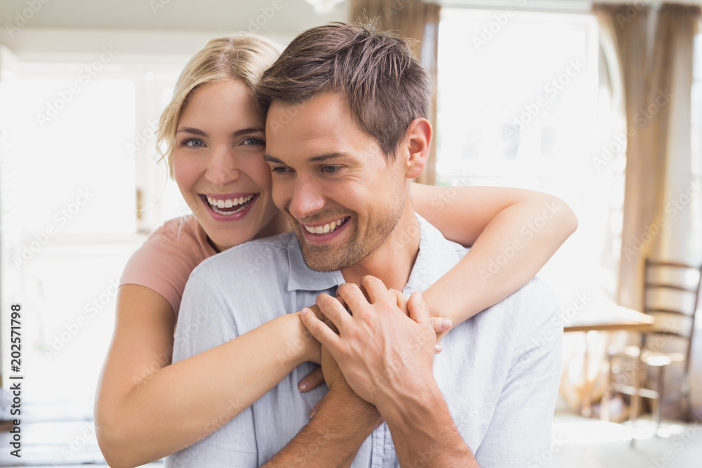 Happy woman embracing man from behind at home Happy woman embracing man from behind at home