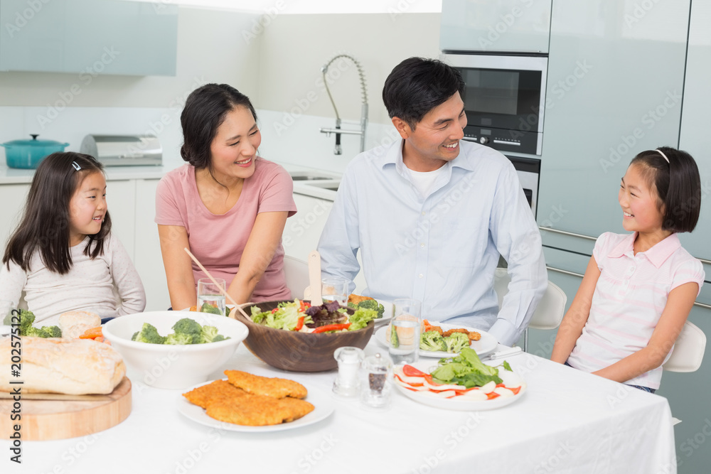 Cheerful family of four enjoying healthy meal in kitchen