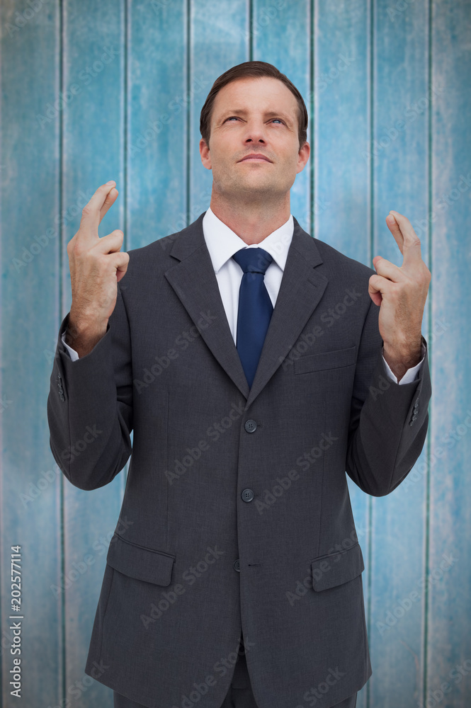 Φωτογραφία Serious businessman with fingers crossed is looking up against wooden planks