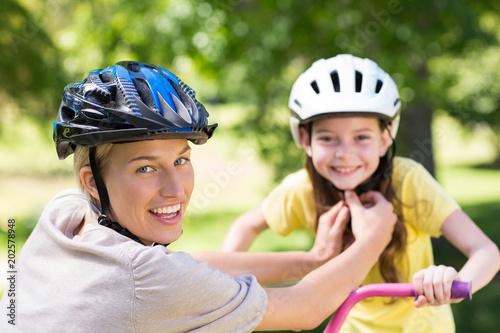 Mother attaching her daughters cycling helmet  © WavebreakmediaMicro