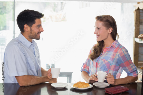Smiling couple with coffee and croissant at coffee shop