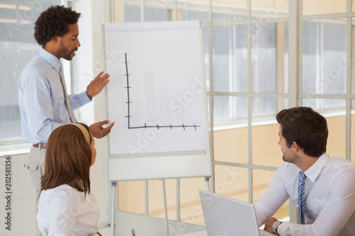 Businessman giving presentation to colleagues in office