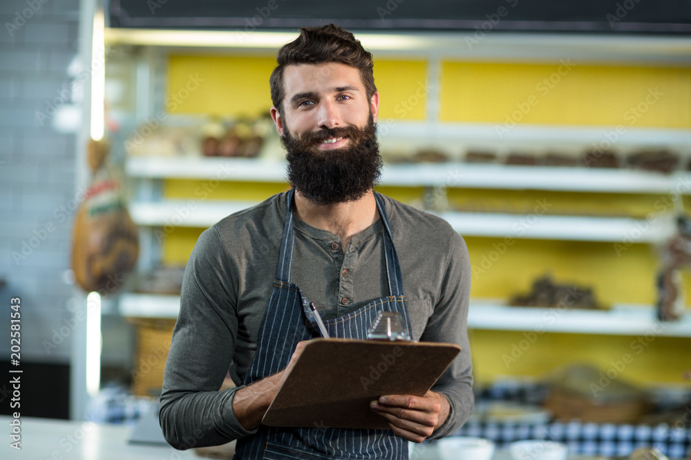 Portrait of salesman writing in clipboard at counter