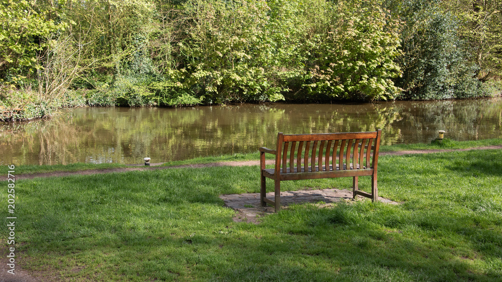 An empty wooden bench built by the canal for people to rest and admire the scene inpeace and quiet An empty wooden bench built by the canal for people to rest and admire the scene inpeace and quiet