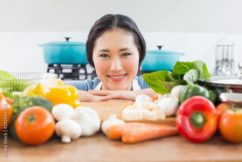 Smiling woman in front of vegetables in kitchen Smiling woman in front of vegetables in kitchen
