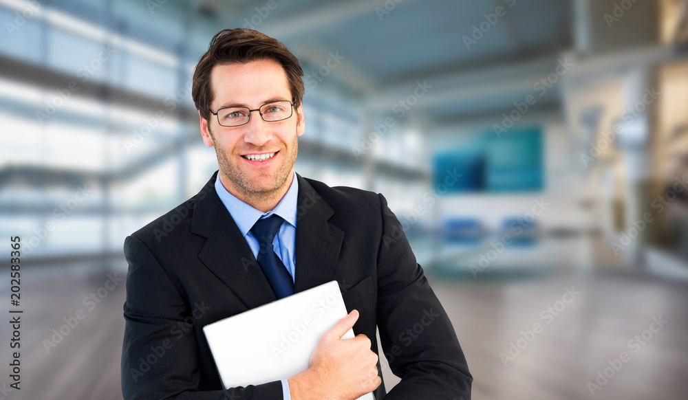 Smiling businessman holding his laptop looking at camera against fitness studio Smiling businessman holding his laptop looking at camera against fitness studio