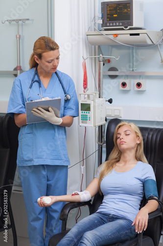 Nurse holding a clipboard while looking at a patient