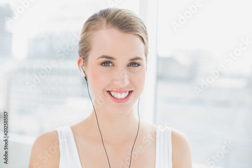 Head shot of cheerful sporty woman listening to music
