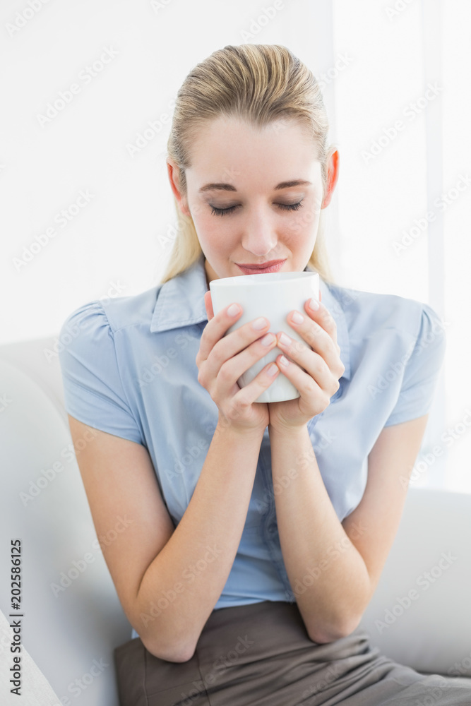 Relaxed calm businesswoman holding a cup smelling it Relaxed calm businesswoman holding a cup smelling it