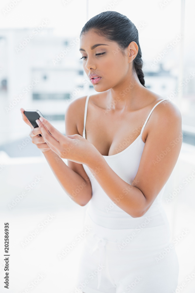 Frowning toned brunette holding mobile phone