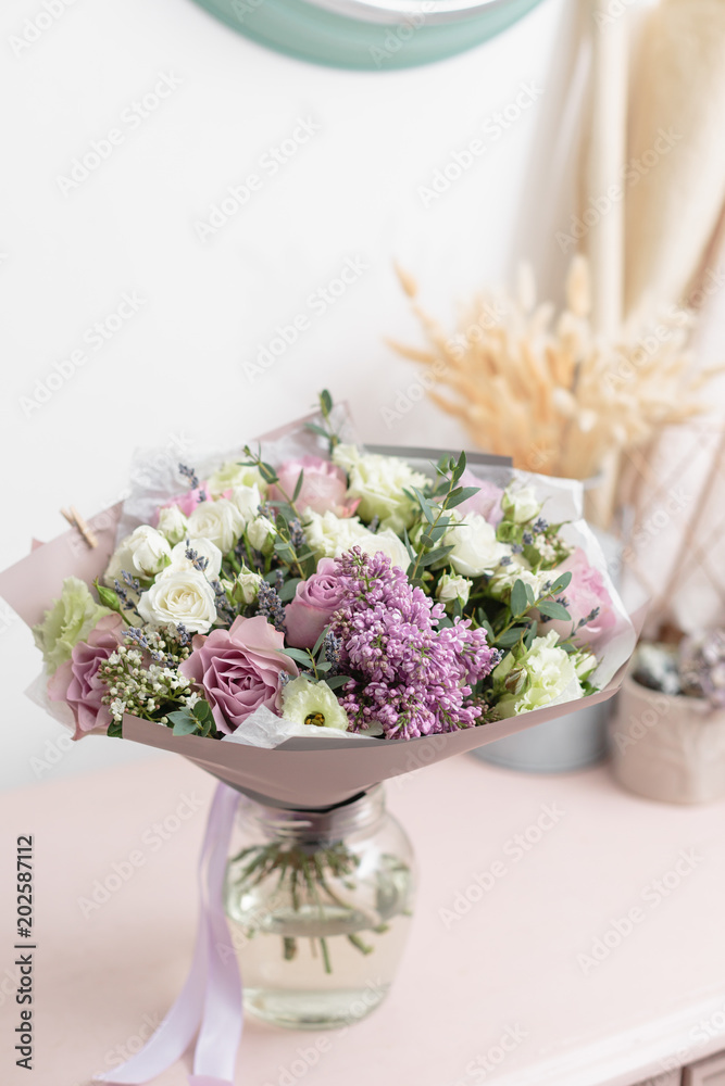 White and lilac bouquet of beautiful flowers on wooden table. Floristry concept. Spring colors. the work of the florist at a flower shop. Vertical photo