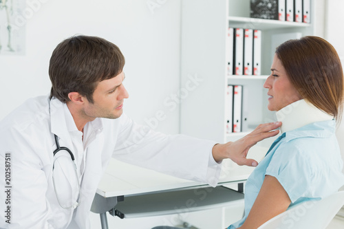 Doctor examining a patients neck in medical office