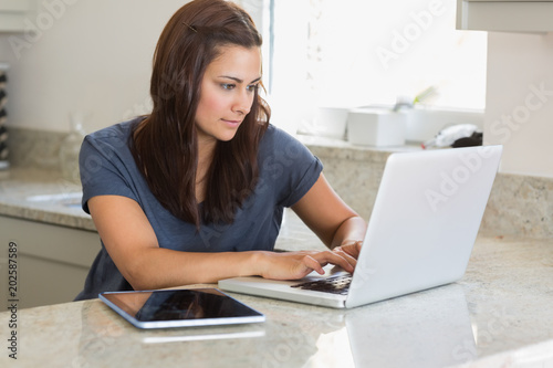 Woman using laptop next to the tablet pc