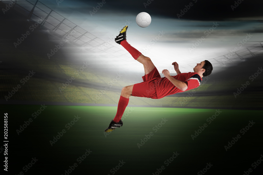 Football player in red kicking in a large football stadium with lights Football player in red kicking in a large football stadium with lights