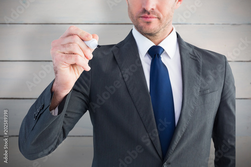 Serious businessman writing with marker against painted blue wooden planks