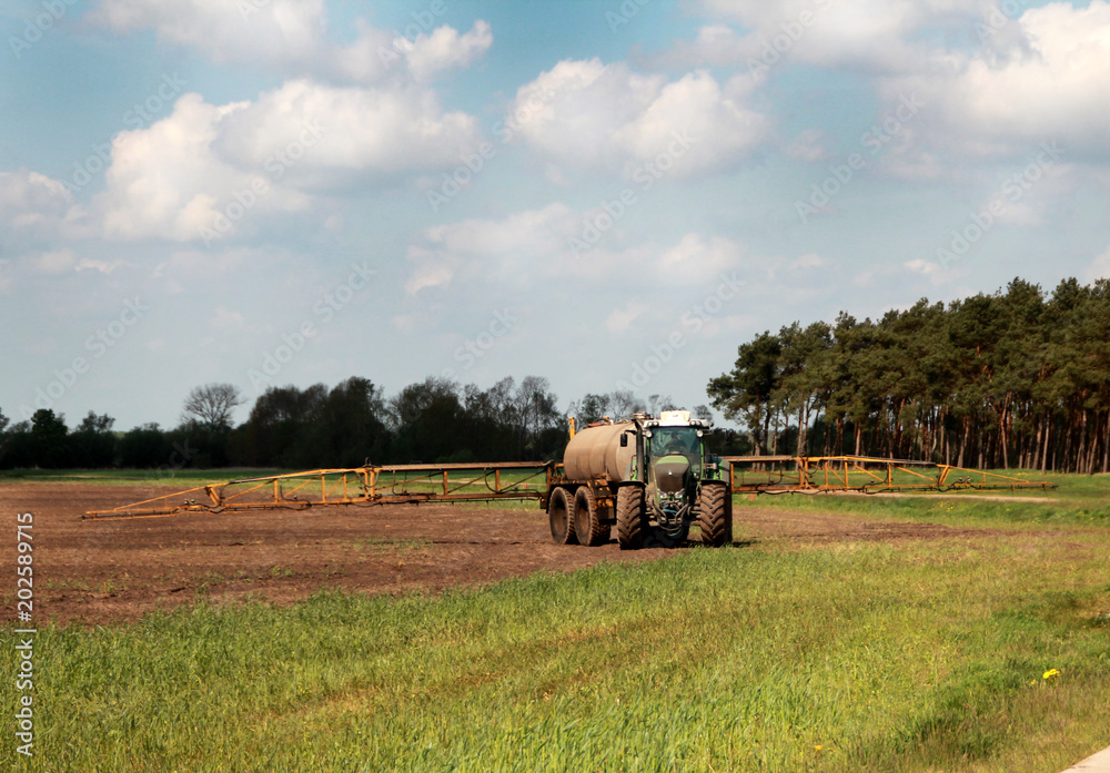 Obraz premium traktor mit tank und düngemaschine auf dem feld