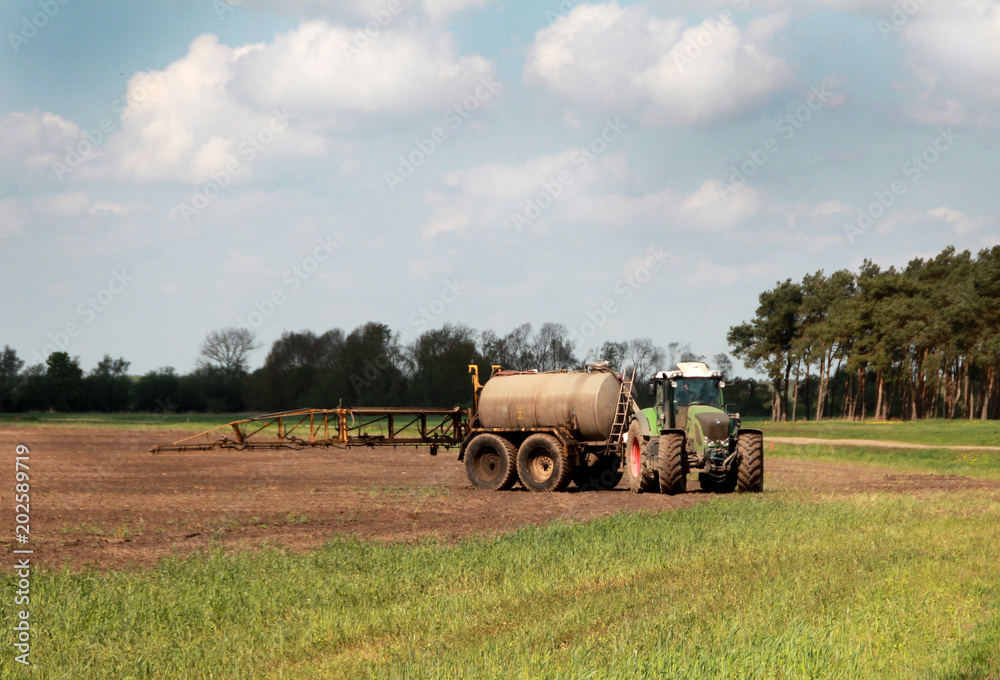 Obraz premium traktor mit tank beim dünger ausbringen auf dem Feld