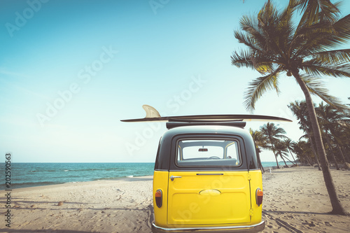 Obraz Tyły zabytkowego samochodu zaparkowanego na tropikalnej plaży (nadmorskiej) z deską surfingową na dachu - wypoczynek w lecie. efekt koloru retro