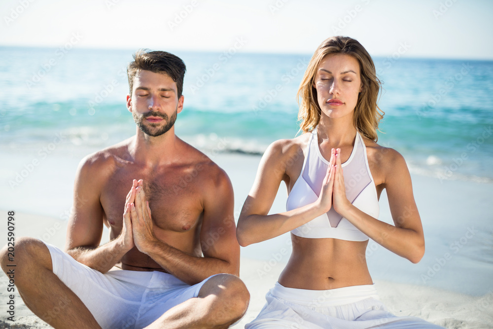 Couple meditating while sitting on shore Couple meditating while sitting on shore