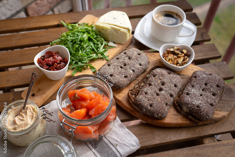 Rye bread sandwich with cream cheese, smoked salmon, arugula, on rustic wooden background, top view. Healthy delicious snack, breakfast or appetizer