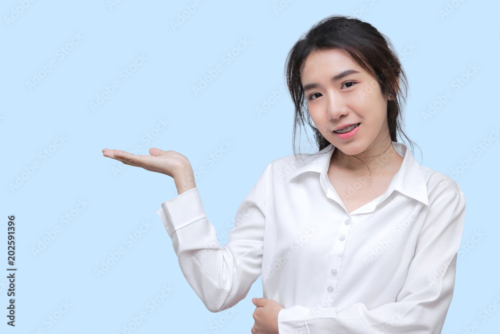 Pretty young Asian woman showing empty copy space on open hand on blue isolated background. Pretty young Asian woman showing empty copy space on open hand on blue isolated background.