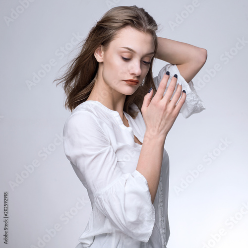 Young blonde in a white shirt on a gray background