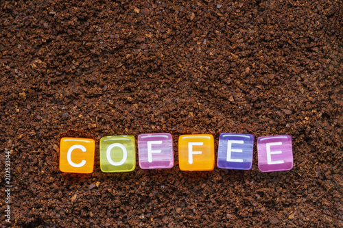Background from ground coffee with the inscription of ground coffee in colored letters on cubes. Closeup, top view
