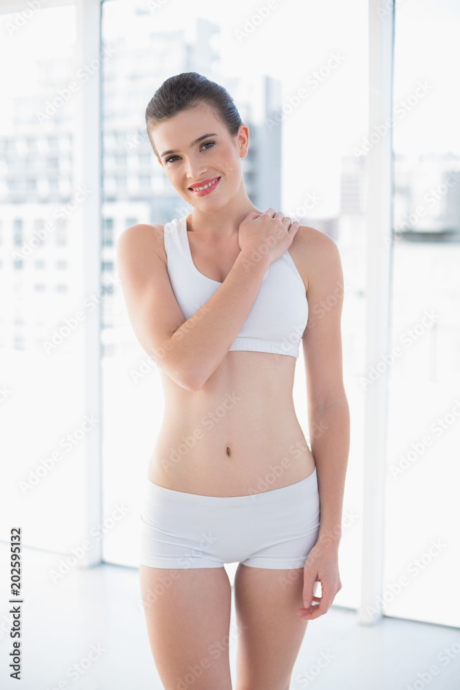 Smiling fit brown haired model in sportswear posing with a hand on the shoulder