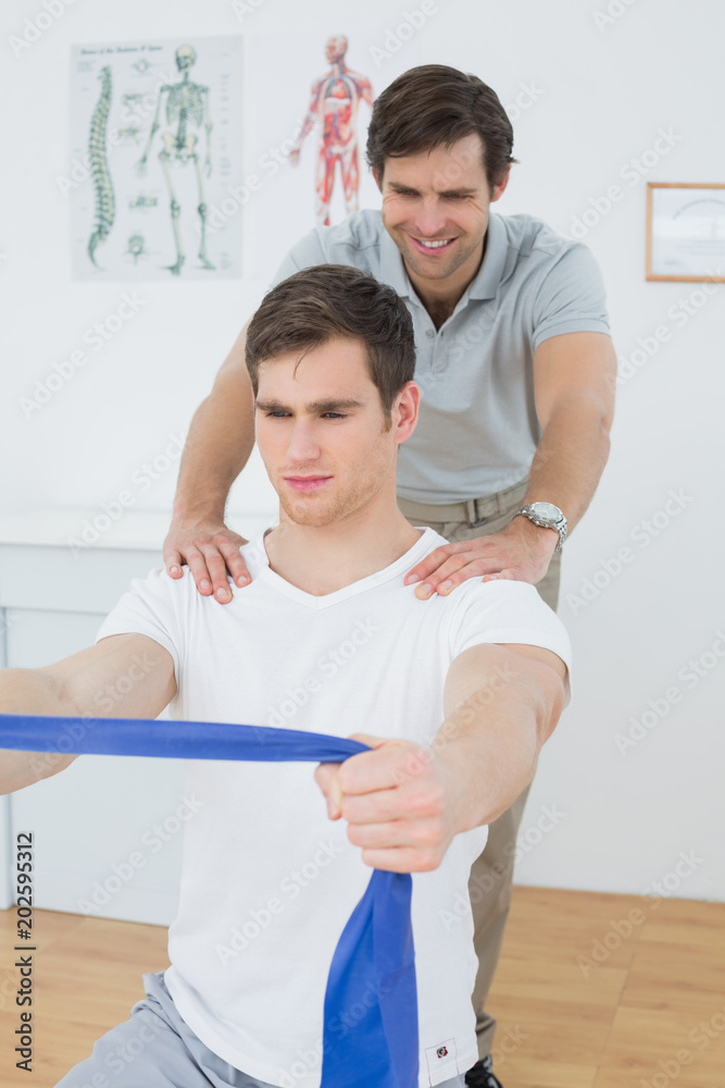 Obraz premium Male therapist assisting man with exercises in office