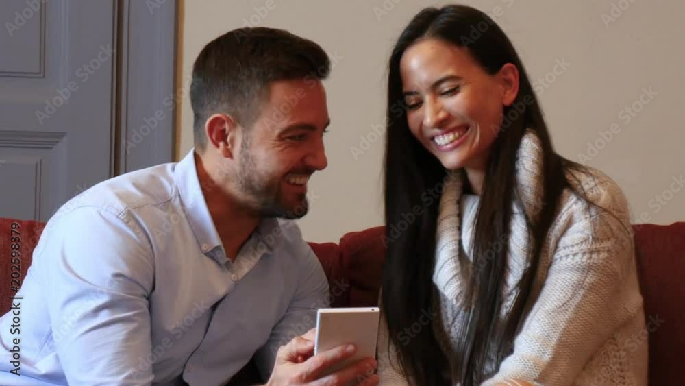 A beautiful young couple in the living room discussing content on a smartphone.
A beautiful young couple in the living room discussing content on a smartphone.
