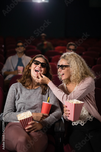 Female friends watching movie in theatre