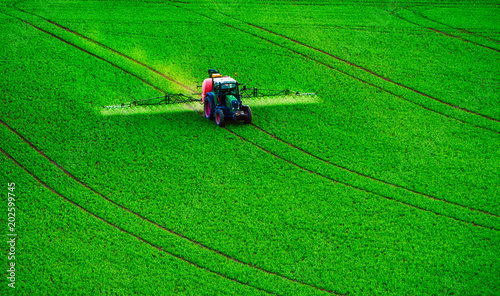 Farm machinery spraying insecticide to the green field, agricultural natural seasonal spring background