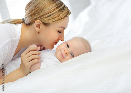 Family portrait of mom and baby in white bed. The concept of family.
