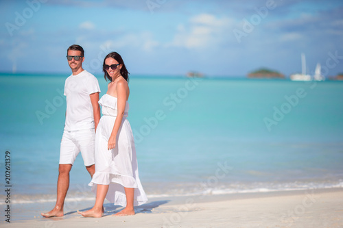 Young couple walking on tropical Carlisle bay beach with white sand and turquoise ocean water at Antigua island