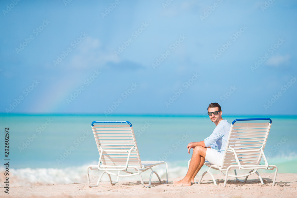 Young man on the beach rest on the chaise-lounge alone