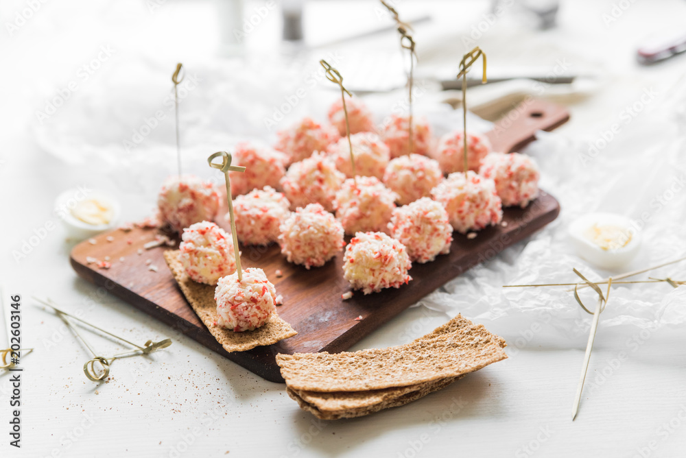 Φωτογραφία Salad in the form of balls of crab sticks on a wooden board on a white wooden ta