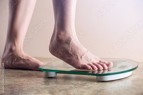 Female feet standing on electronic scales for weight control on light background. Concept of sports training, diets