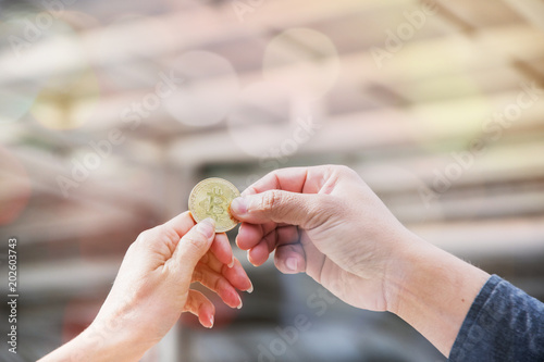 Golden bitcoin in a man's hands trade to customer at upturn of digital virtual currency market. Bitcoin concept background.
