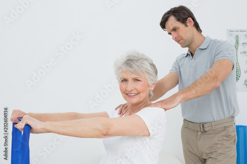 Male therapist assisting senior woman with exercises