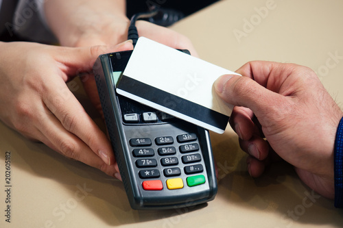 A young womanish blonde is smiling and holding a terminal for payment. credit card, girl, cash. reception in the hotel