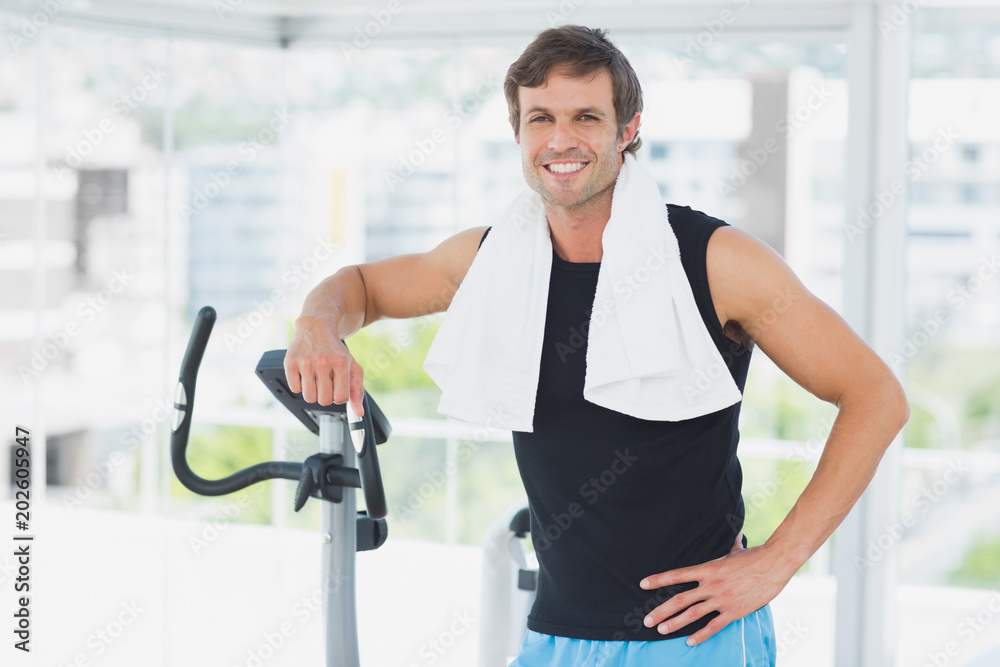 Smiling man standing at spinning class in bright gym Smiling man standing at spinning class in bright gym